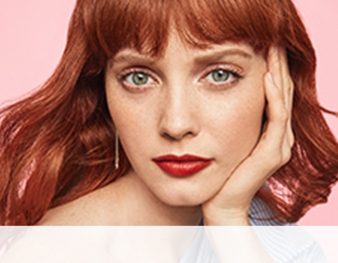 A redhead with bangs in a natural makeup look enhanced with brick red lips