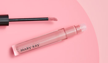 An open tube of shimmery, pink Mary Kay lip gloss is photographed alongside its doe foot applicator and a product smear.
