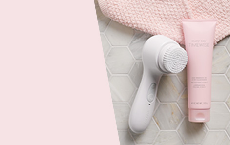 Mary Kay Skinvigorate Sonic Skin Care System shown on heliconical bathroom tile with pink towel and Mary Kay TimeWise Age Minimize 3D 4-in-1 Cleanser