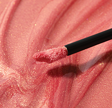 Close-up of one applicator tip against a background of nonsticky Mary Kay Unlimited Lip Gloss