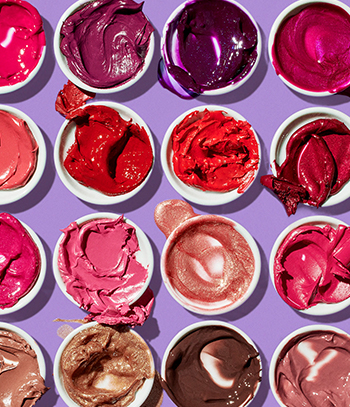 Pots of Mary Kay lip color with overflowing product smears against purple background.